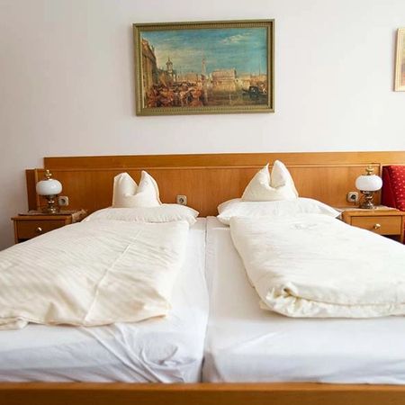 Doppelbett mit weißer Bettwäsche und zwei Nachttischen mit Lampen vor einem Wandbild