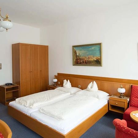Hotel room with double bed, wardrobe, bedside tables, and red sitting area