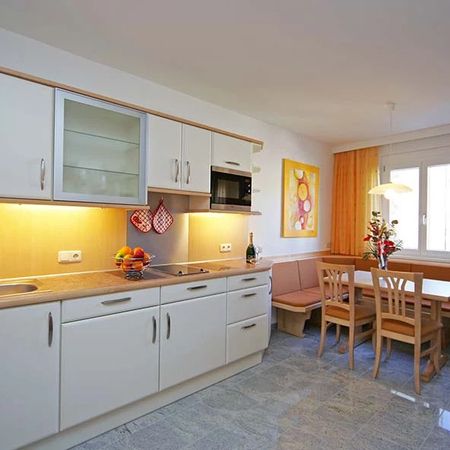 Bright kitchen with white furnishings, stove, microwave, and adjoining dining area with wooden table and chairs