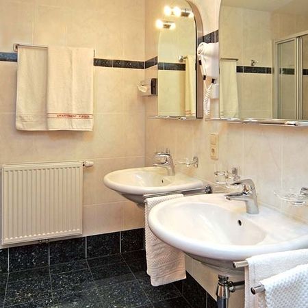 Bathroom with two washbasins, mirror, towels, and hairdryer