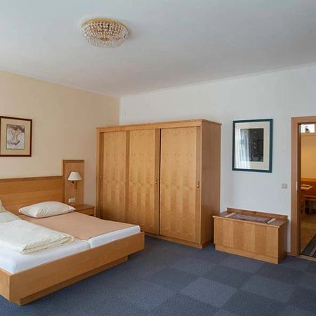 Hotel room with double bed, large wooden wardrobe, and wall pictures