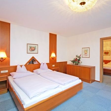 Hotel room with double bed, bedside tables, wall lamps, and dresser with flower arrangement