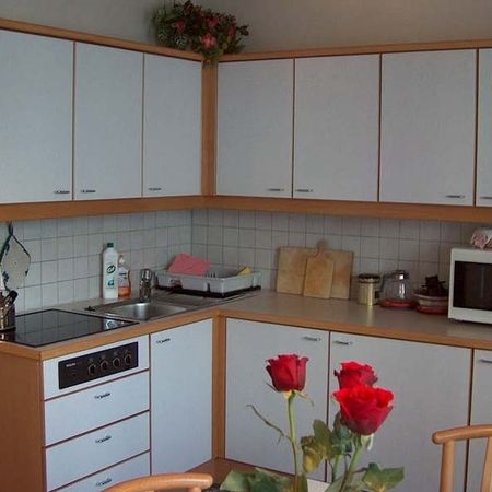 Kitchen with white furnishings, stove, sink, wall cabinets, and kitchen utensils