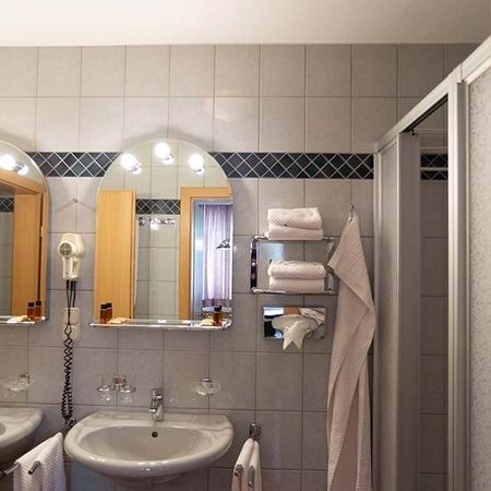 Bathroom with washbasin, mirror, hairdryer, towels, and shower