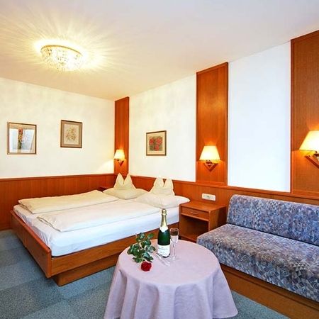 Camera d’albergo con letto matrimoniale, salottino, tavolo con una bottiglia di spumante e una rosa