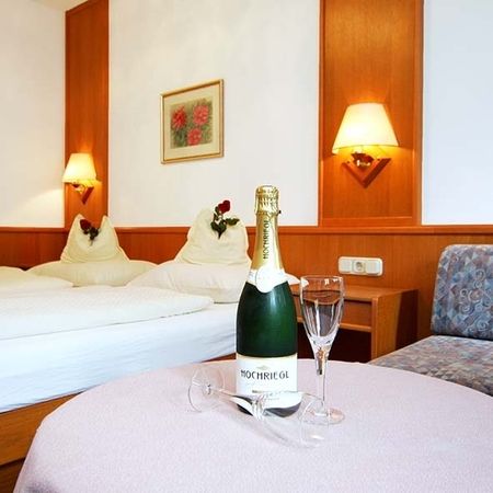 Camera d’albergo con letto matrimoniale, tavolo, bottiglia di spumante e due bicchieri