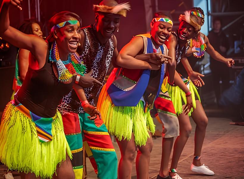 Afrikanische Tanzgruppe in traditioneller Kleidung tanzt auf einer Bühne.