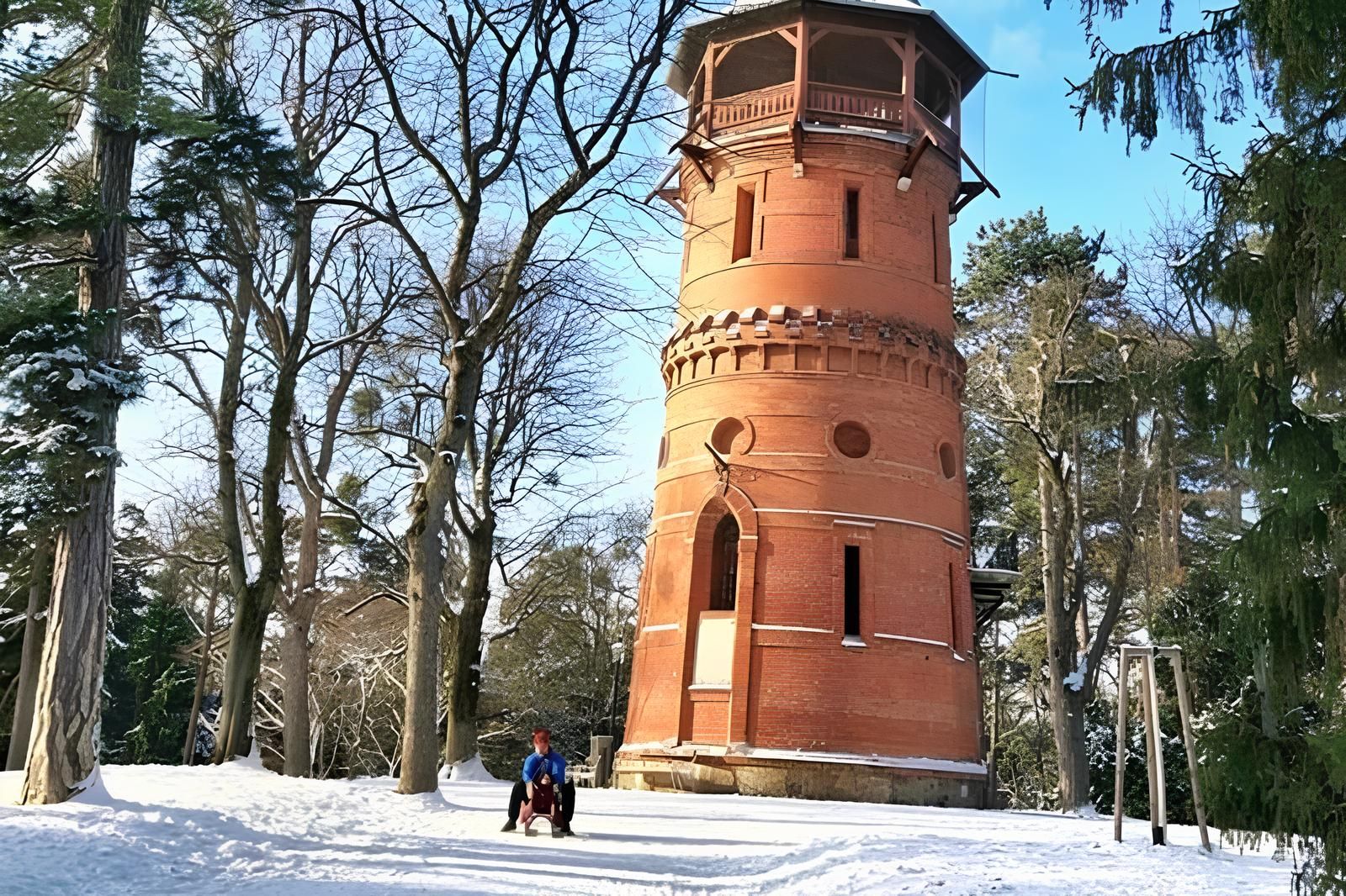 Winterliche Landschaft mit einem roten Ziegelturm auf einer schneebedeckten Lichtung