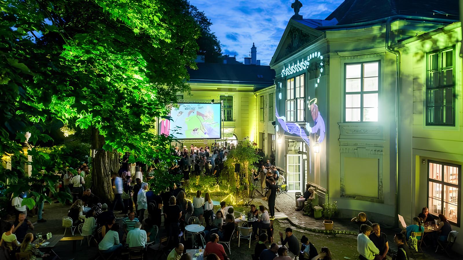Open Air Kino im Innenhof eines Gebäudes in der Nacht.