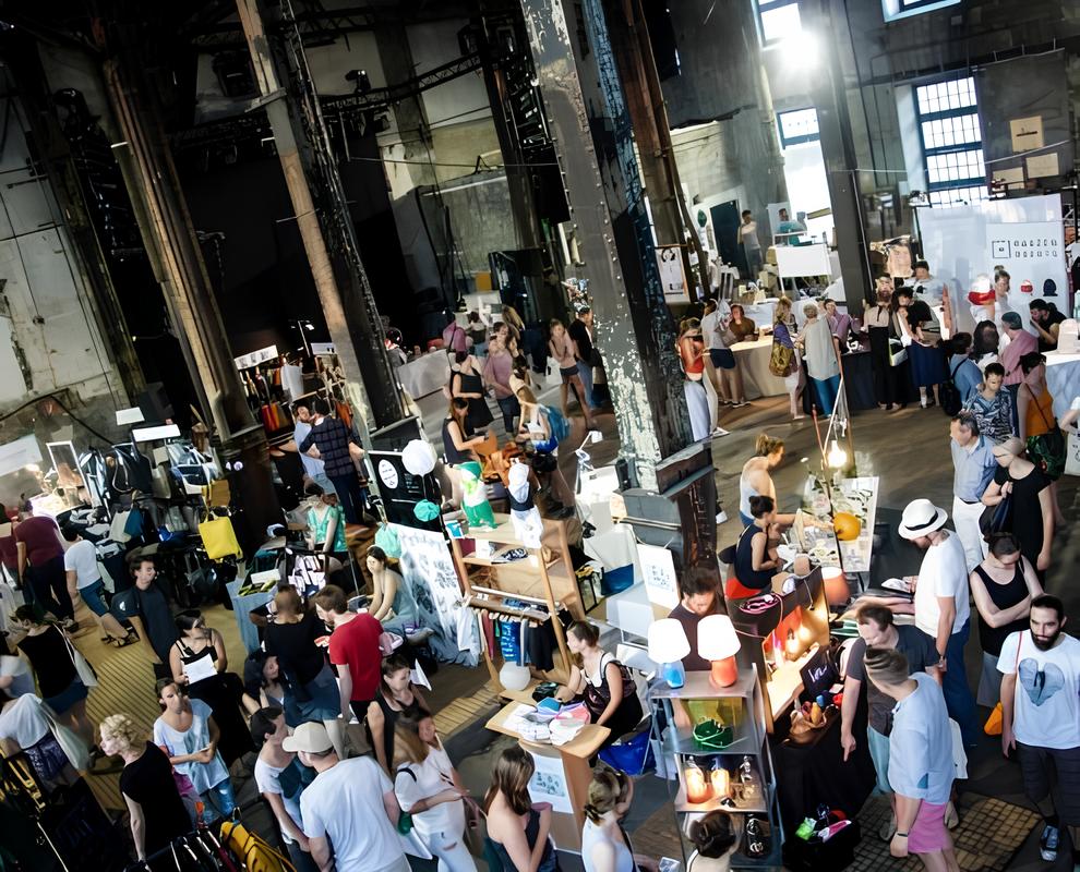 Großer überfüllter Indoor Flohmarkt in einer Industriehalle mit vielen Ständen und Menschen