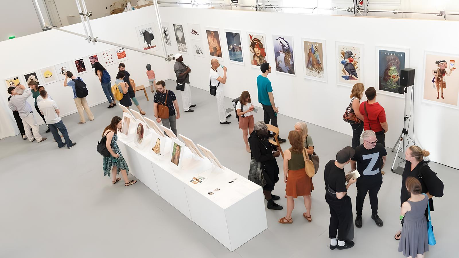 Kunstinteressierte Menschen in einer Galerie mit Bildern an den Wänden.