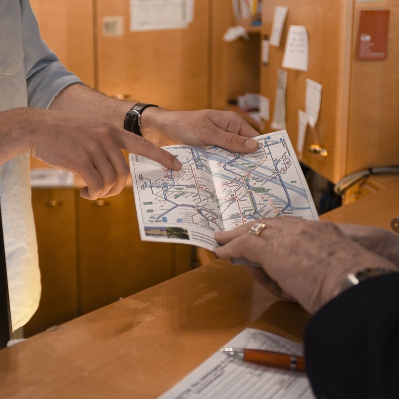 Person pointing at a city map during a consultation at the reception desk