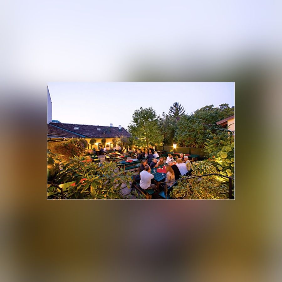 Biergarten am Abend mit beleuchteten Tischen und Gästen die zusammensitzen