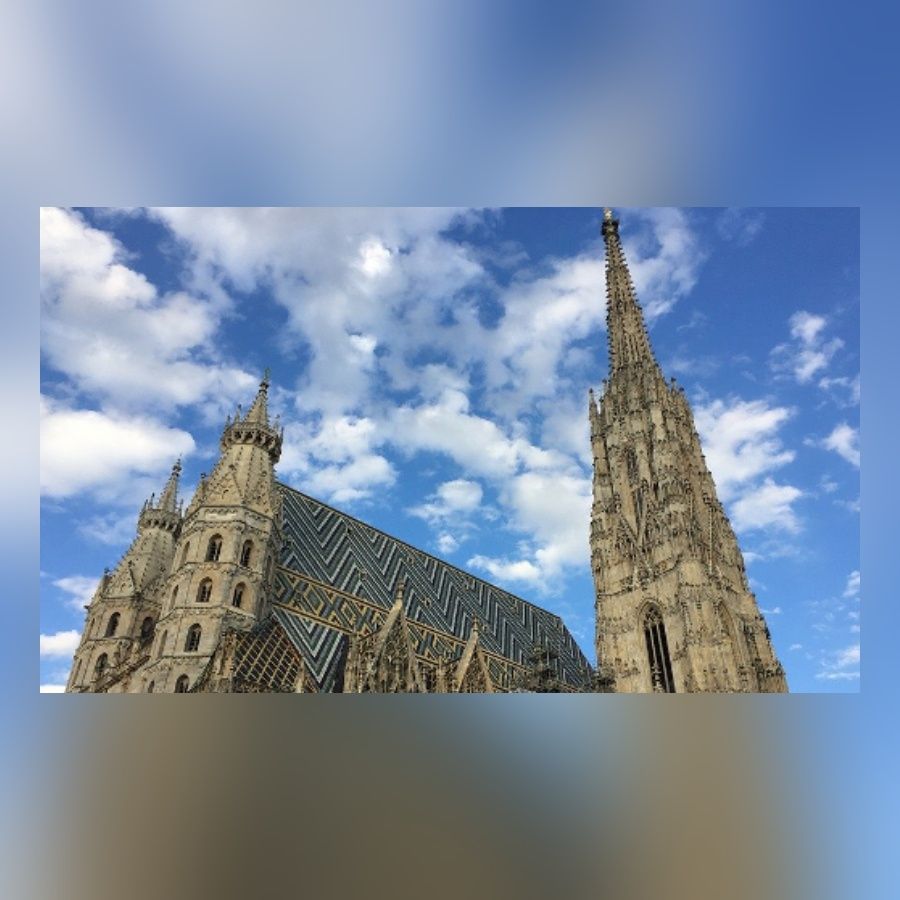 Fassade des Stephansdoms in Wien mit seinem bunten Dach und den zwei Türmen vor einem bewölkten blauen Himmel