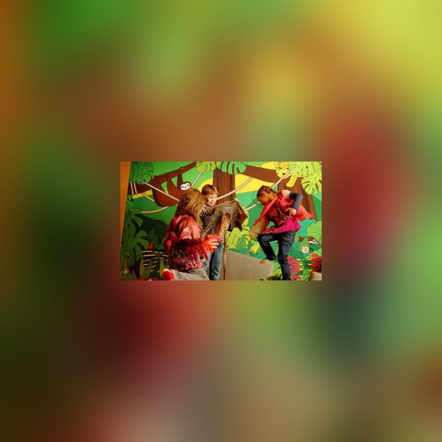 Drei Kinder verkleidet als Tiere spielen vor einer Regenwald Wand.