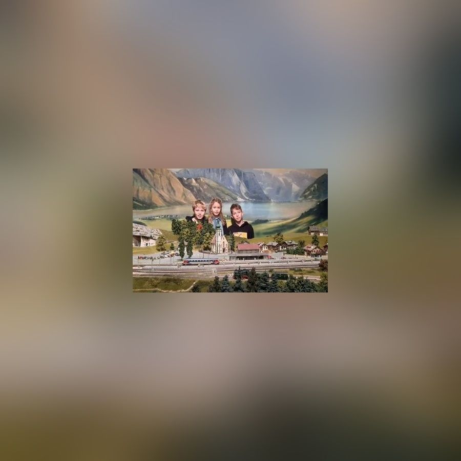 Drei Kinder posieren hinter einer Miniaturlandschaft in einem Museum.