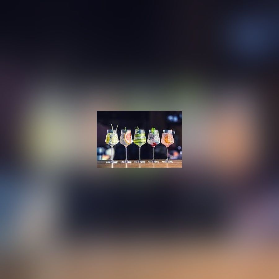 Fünf Cocktails in Weingläsern mit unterschiedlichen Früchten und Garnituren auf einer Theke