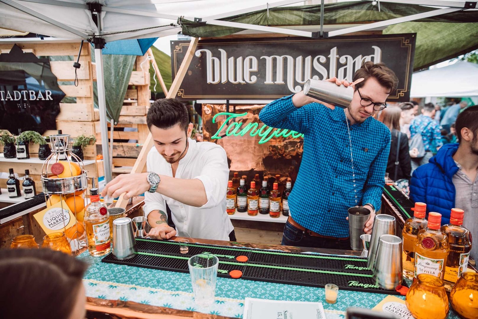 Zwei Barkeeper mixen Cocktails an einem Stand auf einem Markt.