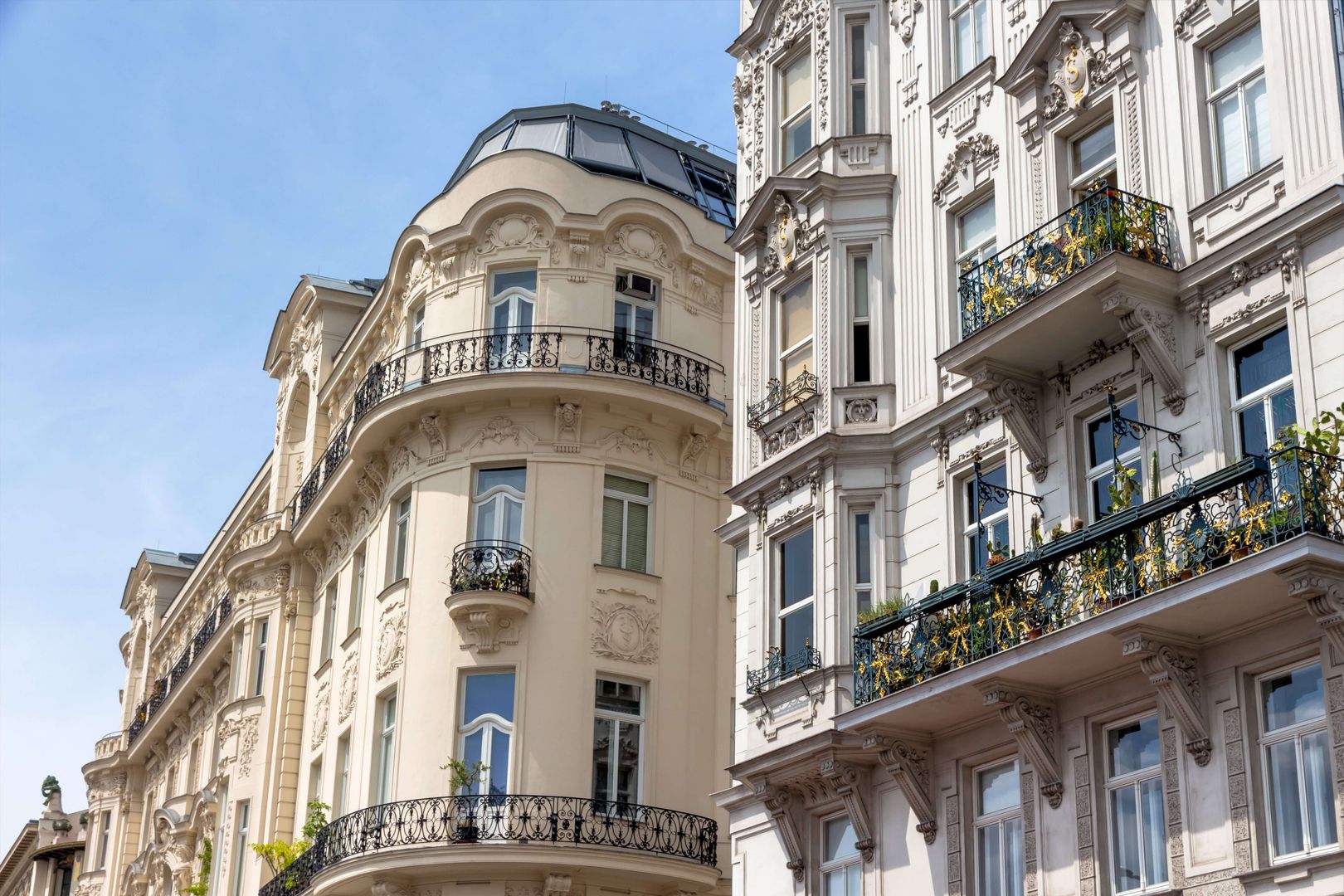 Magnificent historic façades with ornate balconies and stucco details under a blue sky.